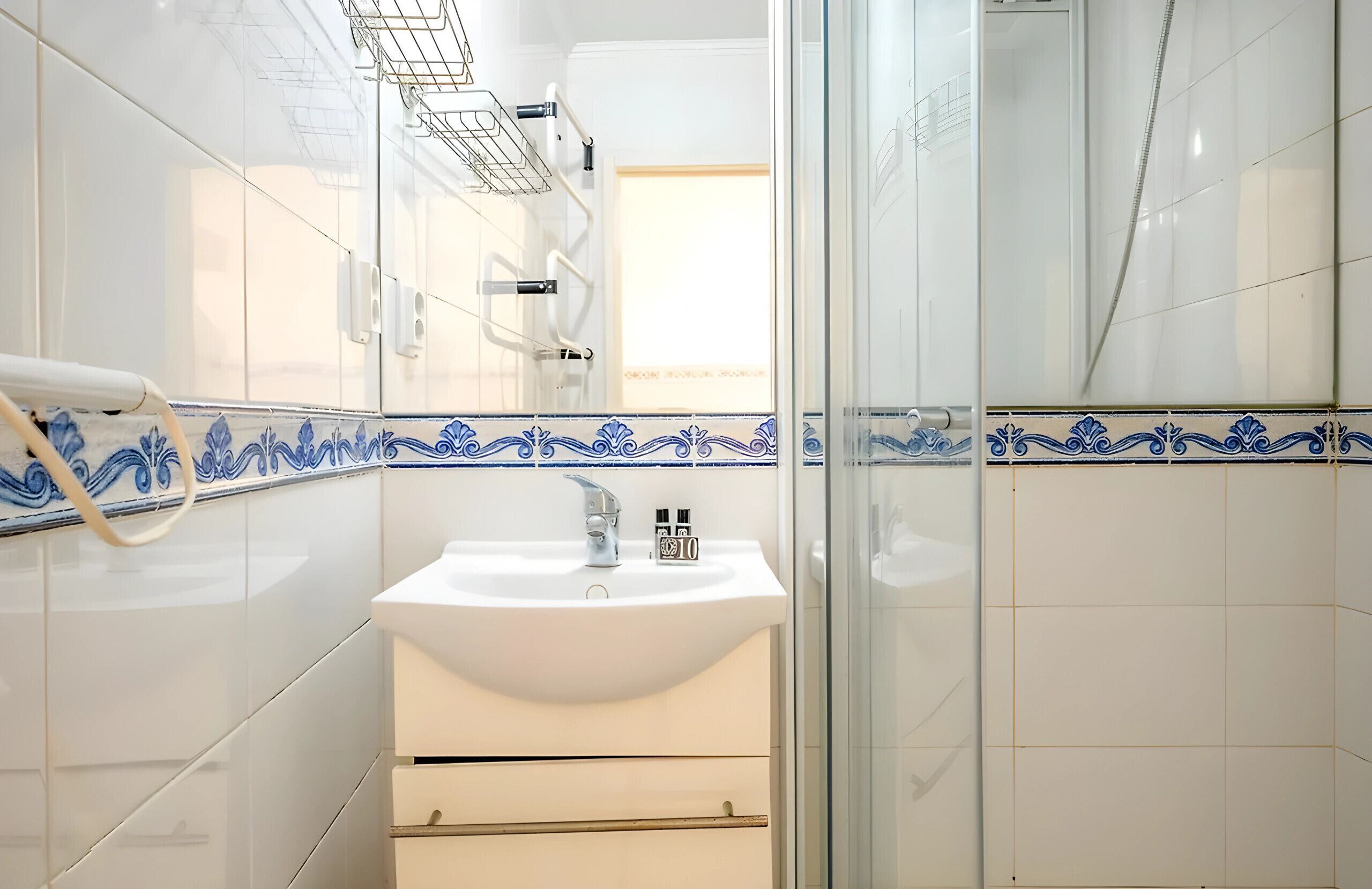 Une salle de bain avec un lavabo blanc, un miroir et un espace douche.