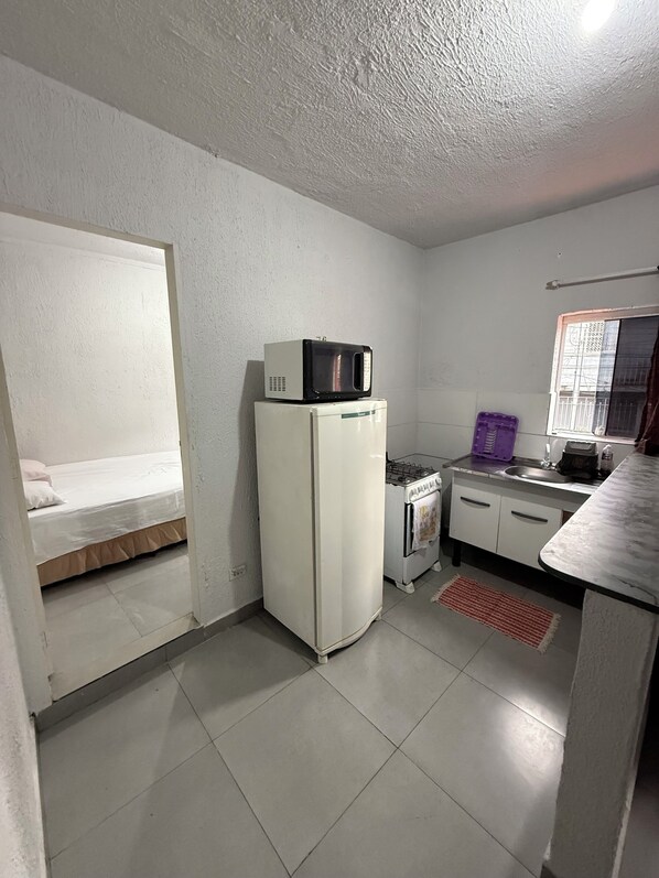 Cocina compacta equipada con refrigerador, microondas, estufa a gas y un lavamanos pequeño.