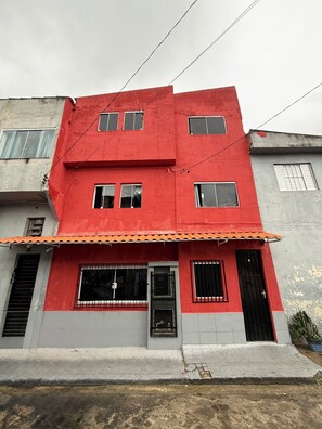 A two-story building with a red facade, multiple windows, and a tiled roof. - Apartamento Confortavel Mobiliado, Zona Norte SP (São Paulo)