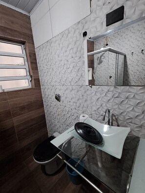 A bathroom with a toilet, sink, mirror, and window. - Apartamento Confortavel Mobiliado, Zona Norte SP (São Paulo)