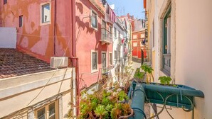 Una calle urbana estrecha con edificios, un tejado de baldosas y una estructura metálica verde.