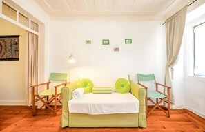 Ein Zimmer mit einem Bett, zwei Stühlen, einer Lampe und einem Fenster mit Vorhängen.