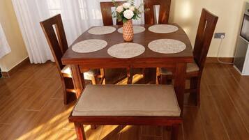 A wooden dining table with four chairs, a bench, and a vase with flowers.