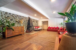 A living room with a stone wall, a fireplace, a sofa, and a large potted plant. - Habitacion compartida 10 pers Wifi Tinajas Cocina (San José de Maipo)