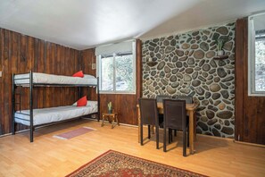 Ein Zimmer mit Etagenbetten, einem Esstisch mit Stühlen, einer Steinsäule und einem kleinen Blumentopf.