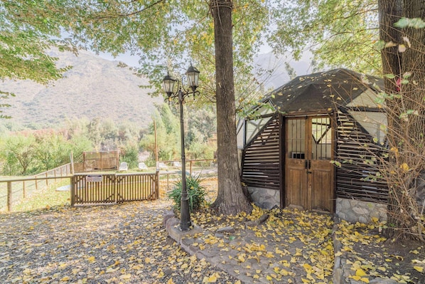 A rustic cabin with a wooden door, a stone foundation, and a metal staircase.
