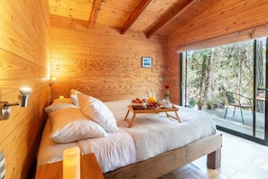 A wooden cabin bedroom with a bed, bedside table, and a breakfast tray.