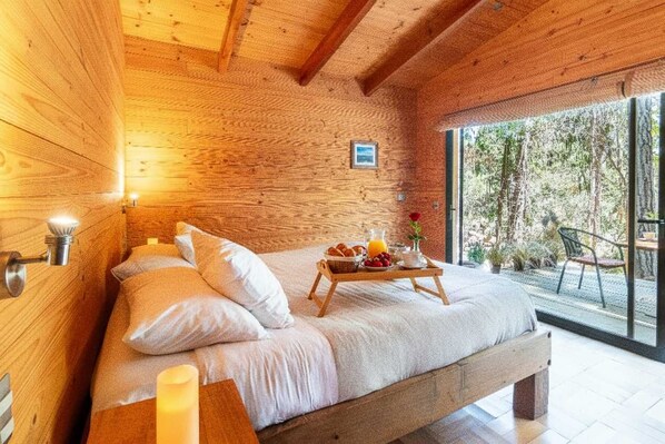 A wooden cabin bedroom with a bed, bedside table, and a breakfast tray.