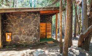 A stone building with a wooden door, a small porch, and a green mat at the entrance.