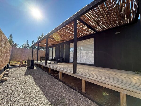 Un espace extérieur abrité, doté de bancs, d’un barbecue et d’une structure à toit de chaume.