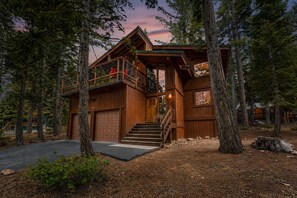 Eine Holzjagdhaus mit Balkon, Garage und einer Treppe zum Eingang.