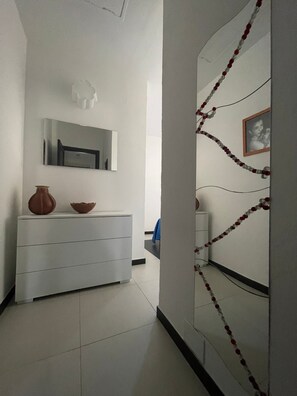 Ein Flur mit einem weißen Kommode, einem Spiegel und einer Wand mit einer Perlenkette.