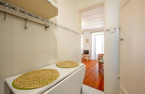 A narrow hallway with a white tiled wall, a white door, and a wooden floor.