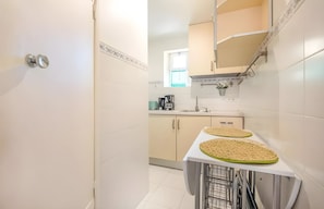 A kitchen with a white countertop, two woven placemats, a coffee maker, and a window with a view.