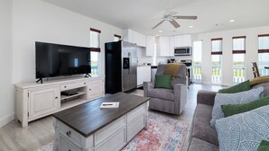 Ein modernes Wohnzimmer mit Flachbildfernseher, Esstisch, Sofa und Deckenventilator.