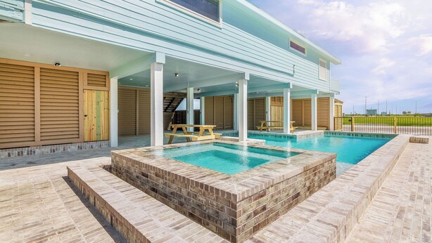 Ein modernes Haus mit Swimmingpool, überdachter Terrasse und Blick auf die umliegende Landschaft.