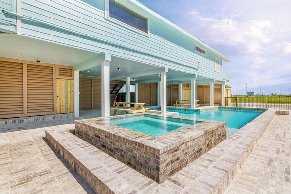 Ein modernes Haus mit Swimmingpool, überdachter Terrasse und Blick auf die umliegende Landschaft.