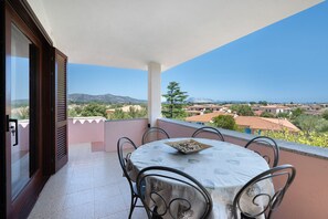 A balcony with a table and chairs, overlooking a residential area with houses and mountains. - 'Citai Sea Viewhouse Puntocasabudoni' Apartment with Sea View, Wi-Fi & Air Conditioning (Suaredda-traversa)