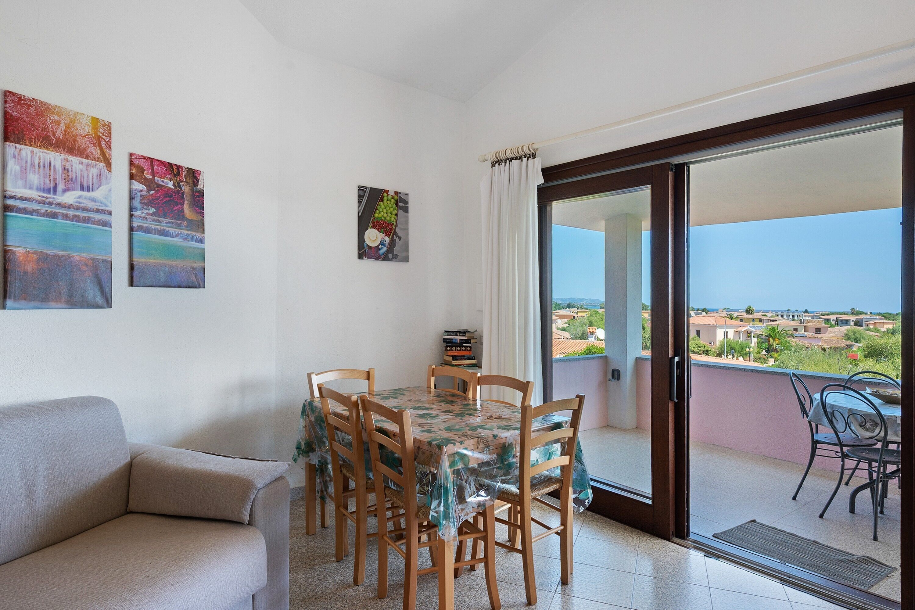 Un balcon avec une table et des chaises, un canapé et une vue sur une ville côtière.