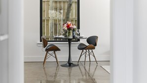 Un coin repas avec une table ronde, deux chaises, un vase avec des fleurs et une bouteille.