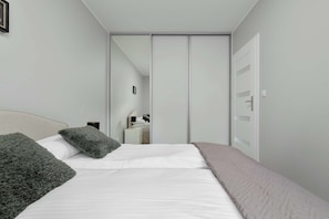 Ein Schlafzimmer mit einem Bett, Kissen, einem Nachttisch, einem Spiegel und einem Kleiderschrank.