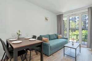 Ein modernes Wohnzimmer mit einem Esstisch für vier Personen, einer Couch und einem kleinen Beistelltisch.
