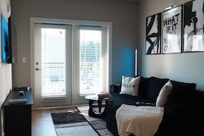 A living room with a sofa, a coffee table, and a door with blinds. - Modern Luxury ATL Apartment• World Cup 2026 (Atlanta)