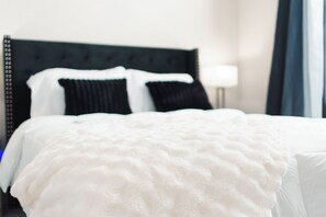 A bed with a white duvet, black headboard, and two black pillows. - Modern Luxury ATL Apartment• World Cup 2026 (Atlanta)