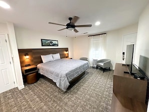 A hotel room with a bed, a desk, a chair, a ceiling fan, and a TV. - Relaxing 2-Bedroom Condo with AC, WiFi in Scenic Canyon Lake (Canyon Lake)