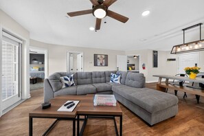 A modern living room with a sectional sofa, a wooden coffee table, and a ceiling fan.