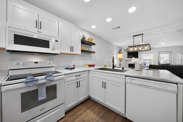 A modern kitchen with white cabinetry, a built-in microwave, and a dishwasher.