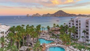 Ett semesterparadis med pool, palmer och utsikt över havet vid solnedgången.