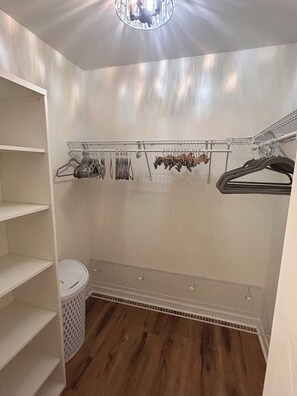 Un dressing avec des étagères, une tringle et un panier à linge.