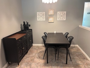 A dining area with a dark wooden table, black chairs, a coffee machine, and decorative wall panels. - Home with private pool near historic area and the beach in Fernandina Beach (Fernandina Beach)