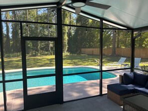 A screened-in area with a view of a backyard, a swimming pool, and outdoor furniture. - Home with private pool near historic area and the beach in Fernandina Beach (Fernandina Beach)