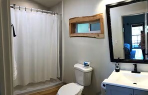 Ein Badezimmer mit Duschvorhang, Toilette, Waschbecken und Spiegel.