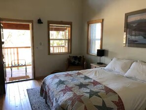 Ein Schlafzimmer mit einem Bett, einer Tür zu einem Balkon, einem Fenster und einem Bild an der Wand.