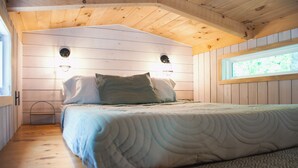 A wooden cabin bedroom with a bed, two wall-mounted light fixtures, and a window. - Beautiful Secluded Tiny Home nestled in Huntingdon,Pa. Perfect couples getaway (Huntingdon)