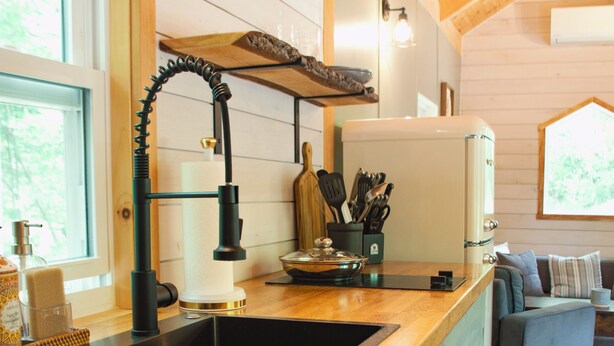 A kitchen with a black sink, wooden countertop, and light green cabinets. - Beautiful Secluded Tiny Home nestled in Huntingdon,Pa. Perfect couples getaway (Huntingdon)
