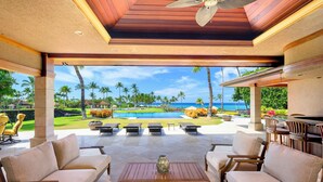 A covered outdoor area with a pool, lounge chairs, and a view of the ocean. - Spacious Ocean View Villa in Beautiful Mauna Lani Resort with AC (Mauna Lani Resort)