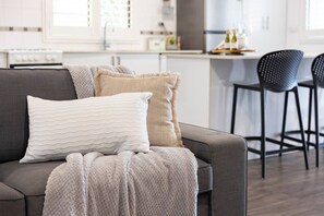 Ein modernes Wohnzimmer mit einer Couch, zwei Kissen und einer Decke.