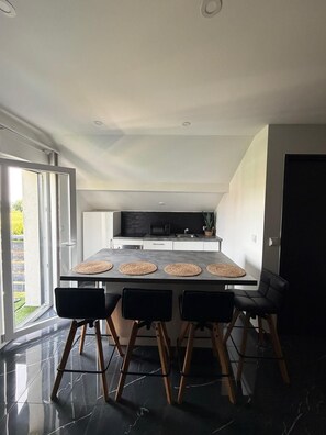 A modern kitchen with a dining area, including a table with four chairs and a large window. - Bao Lounge - Apartment T3 with Pool & Parking (Chavanod)