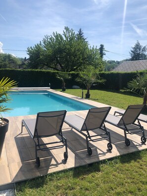 Una piscina con tumbonas y plantas en macetas.