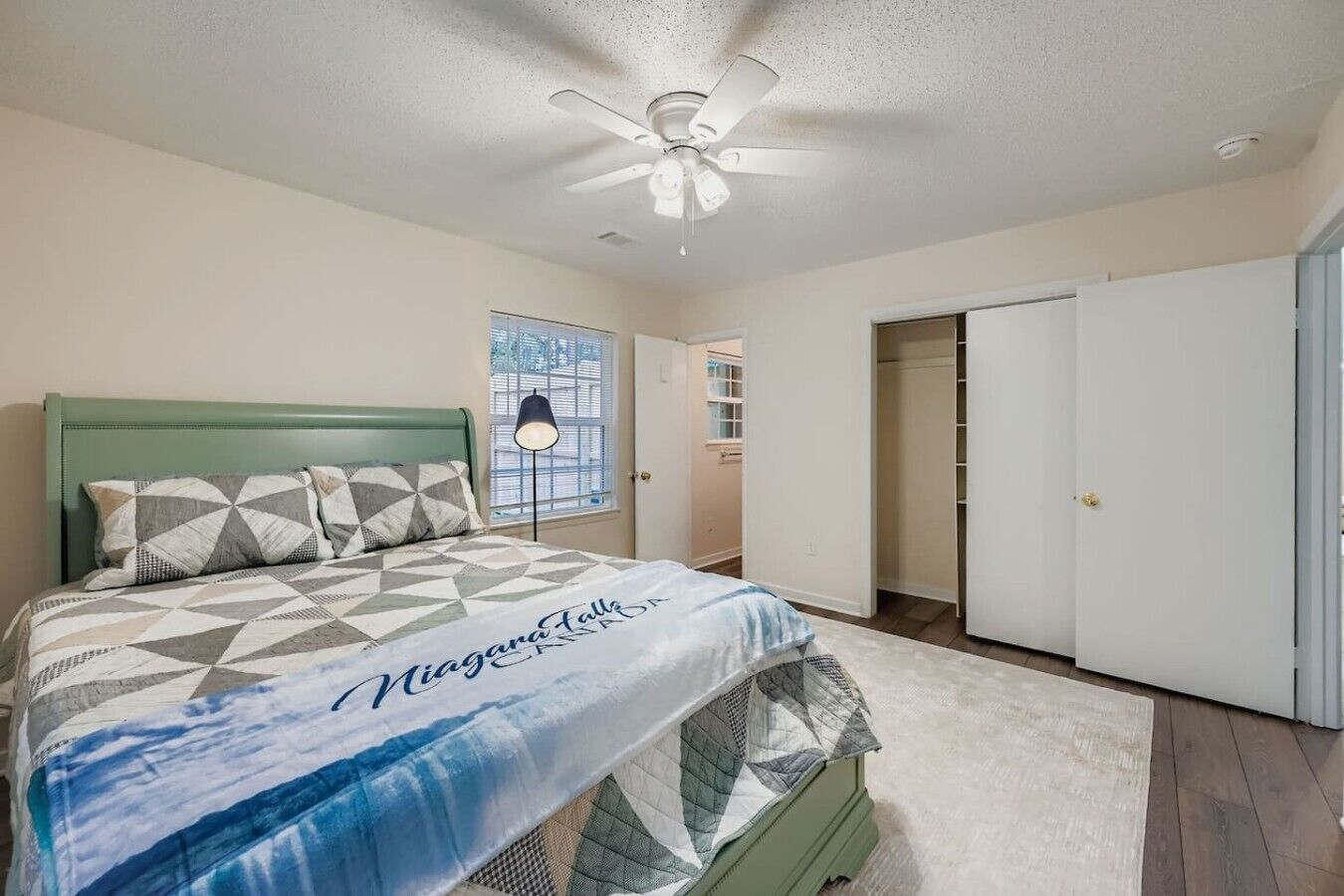 A bedroom with a bed, a ceiling fan, a window, and a closet.