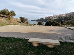 Una zona de grava amb una banca, un estany i turons al fons.