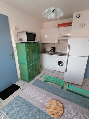 Una cuina compacta amb microones, rentadora i nevera.