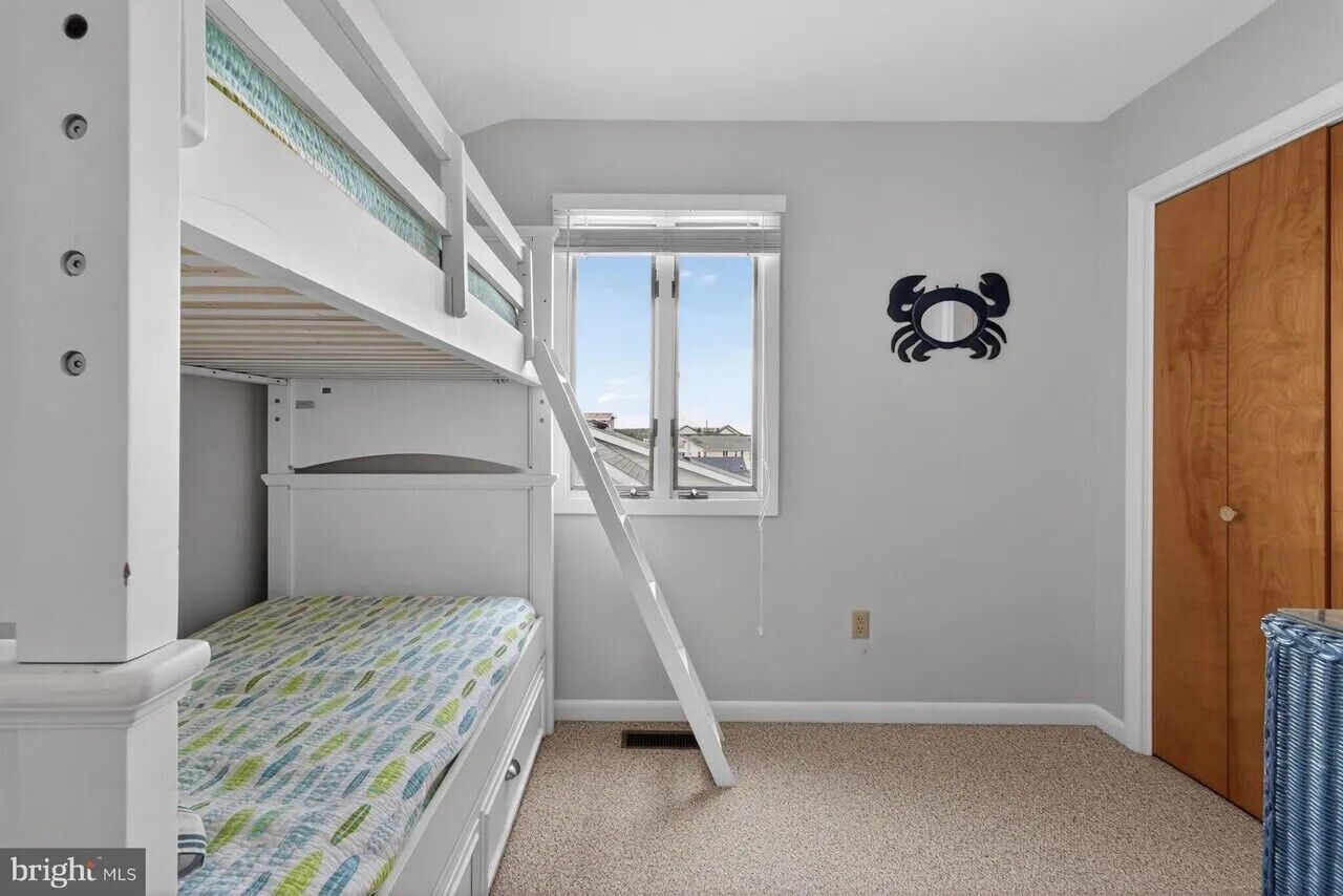 A room with bunk beds, a window, and a door.