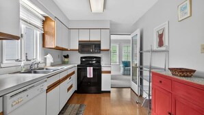 Una cucina moderna con mobili bianchi, un fornello nero e un pensile rosso.