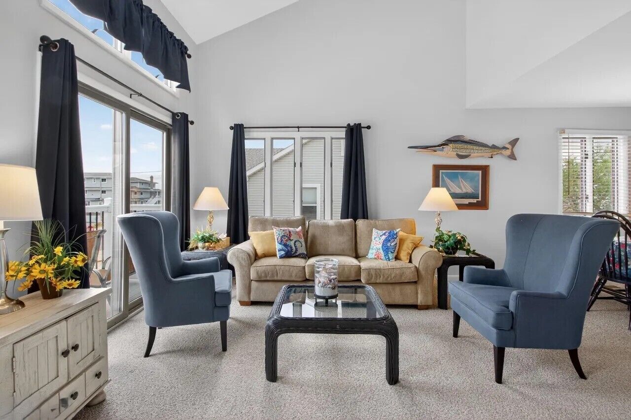 A living room with a sofa, two armchairs, a coffee table, and a window with curtains.