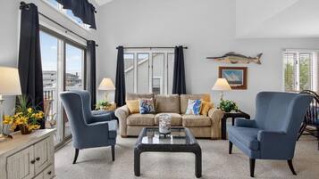 A living room with a sofa, two armchairs, a coffee table, and a window with curtains.
